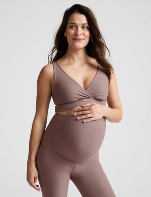 Woman wearing a brown maternity bra and pants against a plain background. 