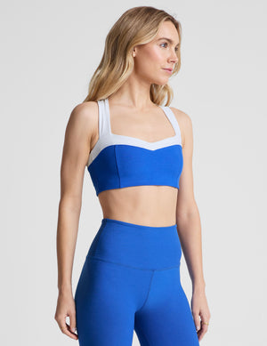 side view of blue self-lined, medium to low support bra top with a colorblock sweetheart neckline panel​, contrast straps, and princess seams. bra is paired with blue high-waisted midi leggings. 