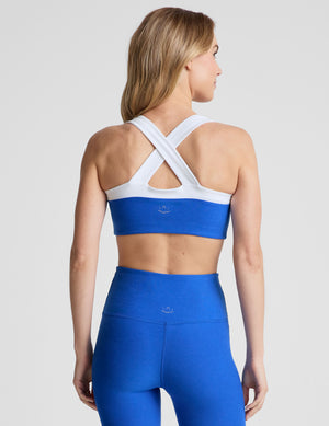 back view of blue self-lined, medium to low support bra top with a colorblock sweetheart neckline panel​, contrast straps, and princess seams. bra is paired with blue high-waisted midi leggings. 