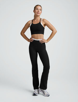 Woman wearing a black and white layered racerback sports bra and leggings on a plain background. 