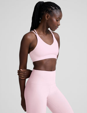Woman wearing a pink sports bra and leggings on a light gray background