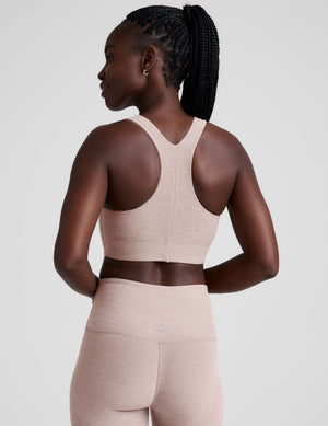 model wearing a pink scoop neck racerback long line sports bra and leggings set on a light gray background. 