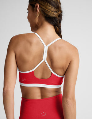 Red sports bra with white straps worn by a person on a plain background. 