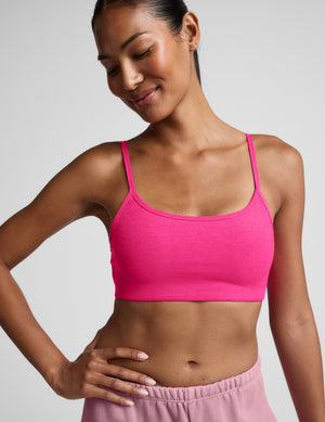 Woman wearing a pink sports bra and shorts on a plain background. 