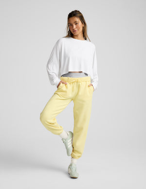 Woman wearing a white top and yellow pants on a gray background. 