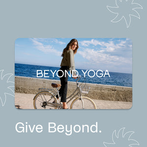 Woman with a bicycle by the ocean, featuring 'Beyond Yoga' branding.