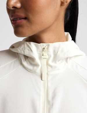 Close-up of a person wearing a light-colored jacket with a zipper.
