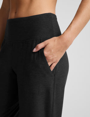 Woman wearing a black bra and black  joggers against a plain background. 