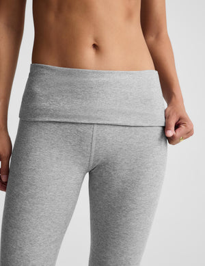 Close-up of a model wearing heather gray high-waisted leggings with a foldover waistband, shown from the torso down against a light gray studio background.