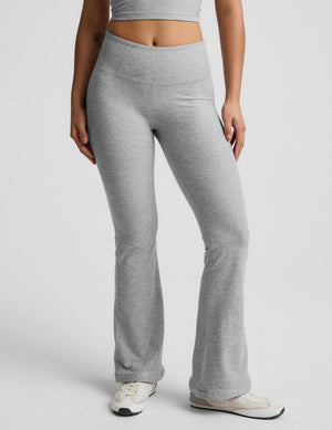 Woman wearing a gray racerback cropped tank top and mid rise bootcut pants against a plain background. 