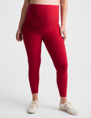 Pregnant woman red maternity leggings against a plain background. 
