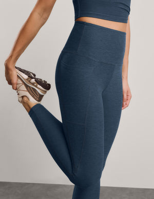 A close-up of a model wearing heathered slate blue high-waisted leggings and a matching cropped tank.
