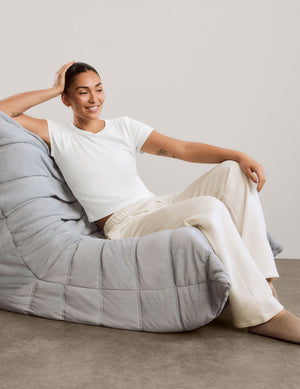 A woman modeling a white short-sleeve cropped top and off-white wide-leg sweatpants against a neutral studio backdrop.