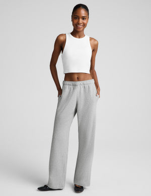 A woman modeling a white sleeveless crop top and light gray wide-leg sweatpants against a light gray studio background.