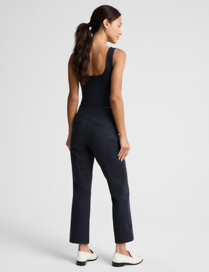 A woman shown from the back wearing a dark navy sleeveless top and matching navy cropped trousers, paired with white loafers, against a light gray studio background.