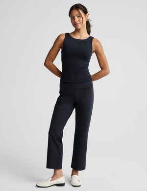 A woman modeling a dark navy sleeveless top and matching navy cropped trousers with white loafers, photographed against a light gray studio background.