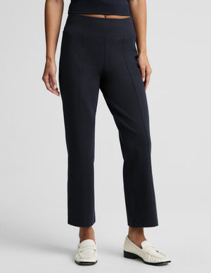 A model wearing dark navy blue cropped trousers with a high waistband, styled with white loafers against a light gray studio background.