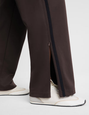 A woman modeling a dark brown sleeveless tank top and matching wide-leg pants against a light gray studio background.