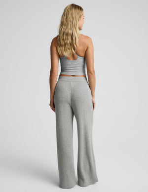 A woman shown from the back wearing a light gray ribbed knit two-piece set consisting of a cropped tank top and matching wide-leg pants, photographed against a light gray studio background.