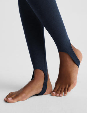 Close-up of a person's feet wearing dark navy blue open-toe slip-on leggings against a light gray studio background.