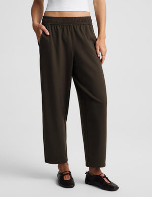 A model wearing dark brown wide-leg cropped pants with an elastic waistband, paired with black Mary Jane shoes, against a light gray studio background.