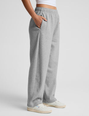 A person wearing light gray heather sweatpants with side pockets, paired with white sneakers, shown from the waist down against a light gray studio background.