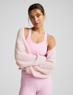 Woman wearing a pink shrug over a matching pink athletic set. 