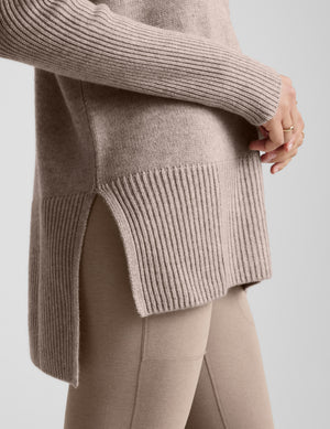 Woman wearing a beige v-neck sweater against a plain background. 