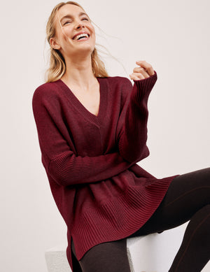 woman wearing a red v-neck sweater sweater against a plain background. 