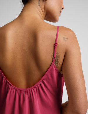 Woman wearing a red mini tank dress against a plain background. 