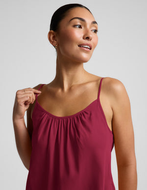 Woman wearing a magenta cupro mini dress and brown sandals against a plain background. 