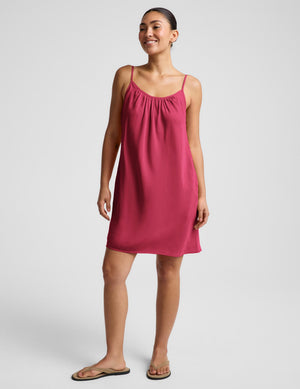 Woman wearing a red mini tank dress against a plain background. 
