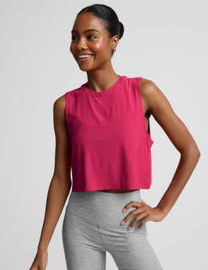 Woman wearing a red cropped tank and gray biker shorts against a plain background. 