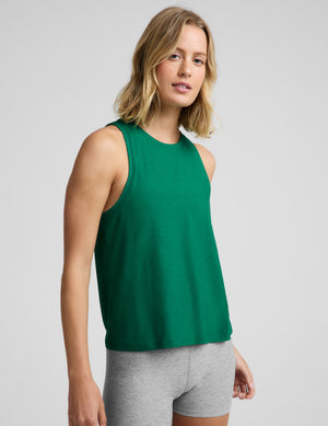 Woman wearing a green lightweight tank top and gray biker shorts against a plain background. 