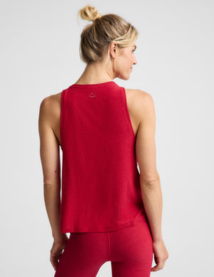 A woman shown from the back wearing a sleeveless red athletic tank top and matching red leggings against a light gray studio background.