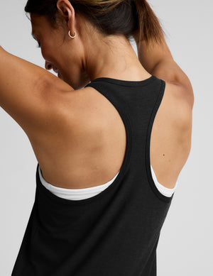 Woman wearing a black tank jumpsuit against a plain background. 