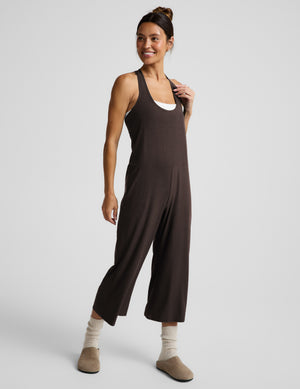 Woman wearing a brown cropped jumpsuit against a plain background. 