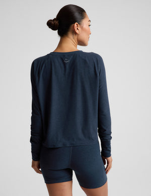 A woman modeling a dark navy blue long-sleeve crop top and matching high-waisted bike shorts against a light gray studio background.