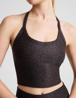 A woman modeling a matching activewear set featuring a dark brown and black leopard print cropped tank and high-waisted leggings, set against a plain light gray background.