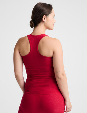 Pregnant woman wearing a red maternity tank top and red maternity leggings against a plain background. 