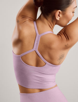 A woman modeling a matching light purple athletic set consisting of a scoop-neck cropped tank and high-waisted leggings, posed against a solid light gray background.