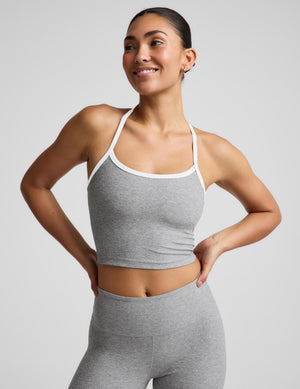 A woman modeling a heather gray sports bra and matching high-waisted leggings against a light gray studio background.
