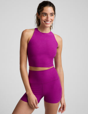 Woman wearing a high-neck cropped tank top and biker shorts against a plain background. 