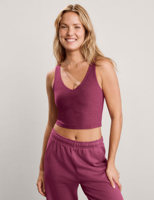 A blonde woman wearing a heathered mauve-purple ribbed crop top and matching jogger pants, photographed against a light gray studio background.