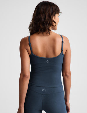 A woman modeling a dark slate blue camisole tank top and matching leggings against a light gray studio background.