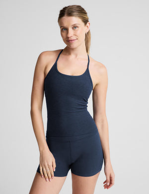 A woman modeling a dark navy blue athletic tank top and matching high-waisted shorts against a light gray studio background.