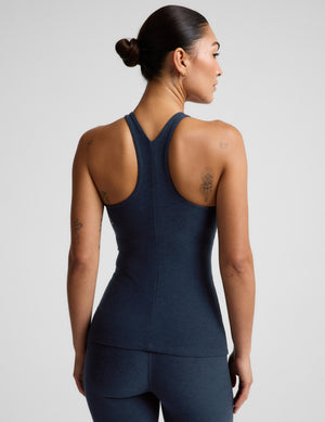 A woman modeling a dark navy blue sleeveless athletic tank top and matching leggings against a light gray studio background.