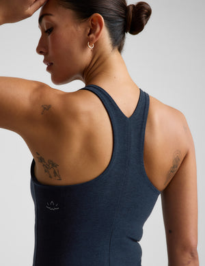 A woman modeling a dark navy blue sleeveless athletic tank top and matching leggings against a light gray studio background.