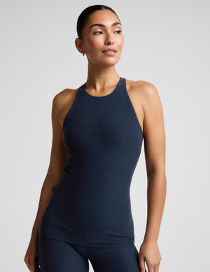 A woman modeling a dark navy blue sleeveless athletic tank top and matching leggings against a light gray studio background.