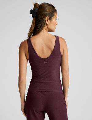 A woman shown from the back wearing a heathered burgundy activewear set, featuring a scoop-neck tank top and matching pants, against a light gray studio background.